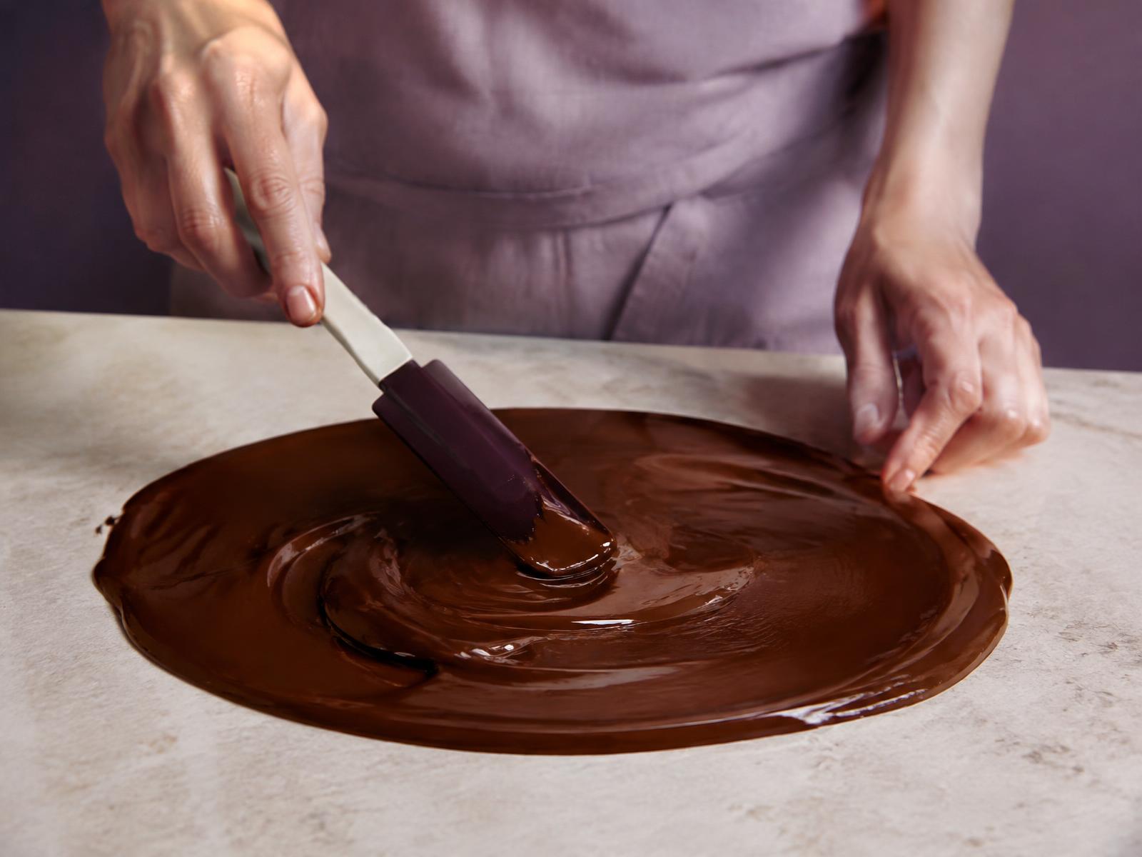 Hands tempering chocolate on a marble stone