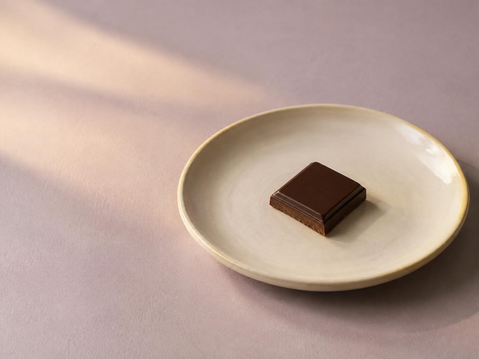 A single square of dark chocolate on a small plate